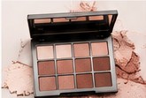 Nine-pan nude eyeshadow palette on a soft pink surface