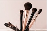 Makeup brushes with black and rose-gold handles in a holder